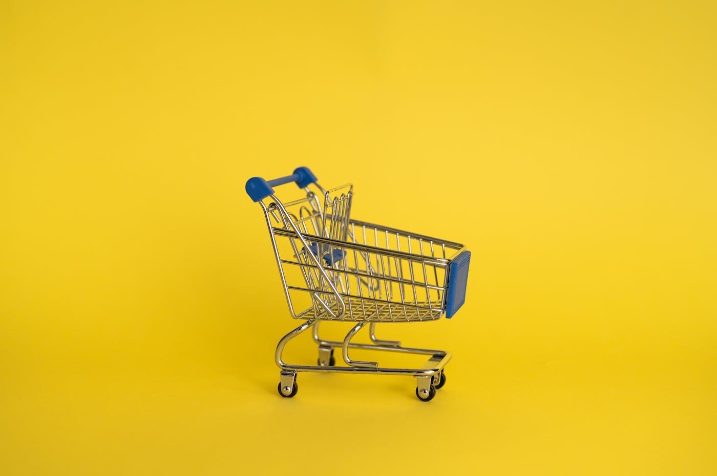 Bunte Mini-Einkaufswagen auf gelbem Hintergrund